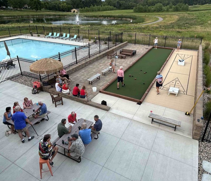 Residents enjoying the Siesta Hills clubhouse patio, pool, games, and tiki bar during a summer community gathering in Mankato, Minnesota.